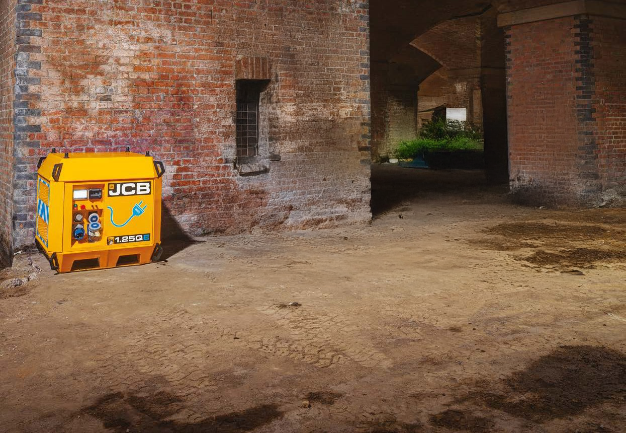A JCB power pack on a farm with old buildings in the background.